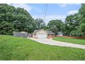 Quaint one-story home with a long driveway, attached garage, and a lush green lawn surrounded by mature trees at 35 Riverbend Dr, Covington, GA 30014