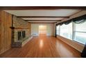Spacious living room with hardwood floors, brick fireplace, wood beams, and large windows at 1001 Wiley Bridge Rd, Woodstock, GA 30188