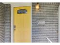 Close up of a yellow front door with glass pane, brick facade and a wall mounted light at 2564 Riggs Dr, East Point, GA 30344