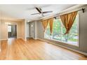 Bright living room boasts hardwood floors, ceiling fan and large windows with warm drapes at 2564 Riggs Dr, East Point, GA 30344