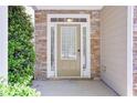 Inviting front door with stone accents and decorative window, framed by manicured landscaping at 5730 Weddington Dr, Cumming, GA 30040