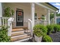 Inviting front porch with flowers, black door, and fresh landscaping at 7095 Evening Dew Dr, Cumming, GA 30028