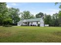 A charming home with a metal roof sits on a sprawling lawn. The house features a two car garage and classic architecture at 11415 Hutcheson Ferry Rd, Chattahoochee Hills, GA 30268