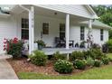 Close up of the front porch, with beautiful landscaping and inviting details with seating and plants in pots at 11415 Hutcheson Ferry Rd, Chattahoochee Hills, GA 30268