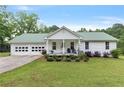 Charming single-story home featuring a green metal roof, white siding, attached garage and a cozy front porch at 11415 Hutcheson Ferry Rd, Chattahoochee Hills, GA 30268