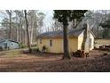 Back exterior of yellow single-story home with brick chimney in an undeveloped yard at 4622 Dogwood Rd, Pine Lake, GA 30072