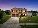 Charming two-story brick home at dusk with a well-manicured lawn and a two-car garage at 85 Foxgrove Cv, Covington, GA 30014