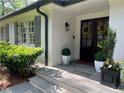 Close up of the front door, featuring sidelights, a beautiful wreath, and tasteful landscaping and planters for a welcoming entry at 1343 Peachtree Battle Nw Ave, Atlanta, GA 30327