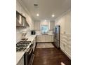 Modern kitchen features white cabinets, stainless steel appliances, marble countertops and backsplash, with hardwood flooring at 1343 Peachtree Battle Nw Ave, Atlanta, GA 30327