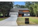Modern two-story home with a dark roof, light wood accents, and a long driveway at 5346 Kelleys Mill Cir, Stone Mountain, GA 30088