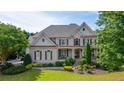 Beautiful two-story home featuring a brick facade, manicured lawn, covered porch, and symmetrical design at 100 Braxton Way, Roswell, GA 30075