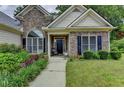 Inviting front entrance with stone accents, a landscaped walkway, and a dark-colored front door at 1815 Sharon Rd, Cumming, GA 30041