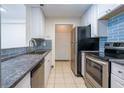 Galley kitchen featuring white cabinets, stainless steel appliances, and blue backsplash at 1074 Peachtree Ne Walk # B404, Atlanta, GA 30309