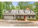 Charming grey home features an attached garage, inviting front entrance, manicured hedges, and mature trees, offering a warm welcome at 130 River Ne Lndg, Sandy Springs, GA 30350