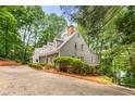 Traditional grey home features an attached garage, inviting front entrance, manicured hedges, and mature trees, providing a private feel at 130 River Ne Lndg, Sandy Springs, GA 30350