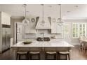 Gourmet kitchen with a large center island, white cabinetry, marble countertops, and pendant lighting at 670 Trinity Pl, Suwanee, GA 30024
