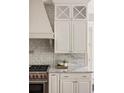 Close-up of the kitchen with stainless steel appliances, custom cabinetry, and elegant marble backsplash at 670 Trinity Pl, Suwanee, GA 30024
