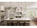 Bright kitchen featuring a large center island with seating, pendant lighting, and professional-grade appliances at 670 Trinity Pl, Suwanee, GA 30024