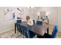 Dining room with abstract paintings, black table, blue chairs, and modern chandelier create an elegant and inviting atmosphere at 3064 Steinbeck Way, Atlanta, GA 30344