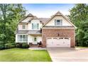Well-maintained home with brick accents, a two-car garage, inviting front porch, and manicured landscaping at 596 Deadwood Trl, Locust Grove, GA 30248