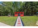 A charming red shed featuring black shutters and brick walkway at 1424 Brighton, Loganville, GA 30052