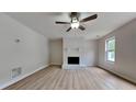 Bright living room featuring a white painted brick fireplace and light laminate flooring at 5634 Windwood Rd, Atlanta, GA 30349