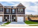 Close-up of a townhome featuring a garage, gray siding, brick accents, and a well-manicured lawn at 231 Ivey Ter, Temple, GA 30179