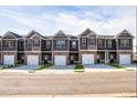New row of townhomes with neutral exteriors, brick accents, and white garage doors at 231 Ivey Ter, Temple, GA 30179