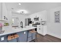 Modern kitchen with white cabinetry, stainless steel appliances, island with bar stools, and hardwood floors at 2586 Abbotts Glen Nw Dr, Acworth, GA 30101