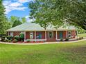 Attractive brick home with a long, covered front porch, surrounded by lush landscaping at 2620 Dr Bramblett Rd, Cumming, GA 30028