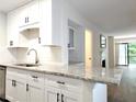 Bright kitchen featuring white cabinets, granite countertops, and a view to the living room at 3304 Pine Heights Ne Dr, Atlanta, GA 30324