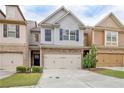 Attractive townhome exterior with a two-car garage, stone accents, and a well-maintained lawn at 2243 Knoxhill Se Vw, Smyrna, GA 30082