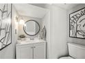 Stylish half bathroom featuring a modern vanity, round mirror, and contemporary artwork at 4131 N Gloucester Pl, Atlanta, GA 30341