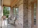 Inviting front porch with brick facade, framed by large windows, and cozy seating area at 5725 Lake Oak Lndg, Cumming, GA 30040