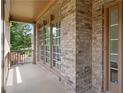 Charming front porch featuring brick facade, and natural wood door with windows and trim at 5725 Lake Oak Lndg, Cumming, GA 30040