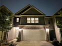 Townhome exterior with two-car garage, landscaping, and neutral color scheme at nighttime at 2264 Shetley Creek Dr, Norcross, GA 30071