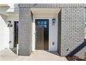 Inviting front door of unit 106 with gray brick, a porch light, and modern hardware at 101 Mission Se Way # 101, Atlanta, GA 30315