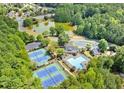 Aerial view showcases community amenities: pool, tennis courts, clubhouse, and a tranquil pond amid lush greenery at 2049 Mclain Nw Rd, Acworth, GA 30101