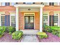 Close-up of a brick home's front entrance with white columns, dark shutters, and trimmed greenery at 2049 Mclain Nw Rd, Acworth, GA 30101