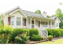 Charming home featuring a welcoming front porch and beautifully landscaped front yard with lush greenery at 68 Paradise Pointe, Douglasville, GA 30134