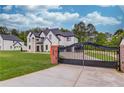 Elegant estate featuring a grand entrance gate and a sprawling green lawn that complements the home's architecture at 3205 Bold Springs Rd, Dacula, GA 30019