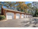 View of garages, each with white doors, constructed of brick, with mature trees overhead at 3302 Dogwood Dr # 328, Atlanta, GA 30354