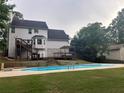 Back exterior showing a two-story home with an outdoor deck, steps and a large inground swimming pool at 1020 Travitine Trl, Loganville, GA 30052
