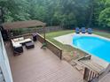 Deck view of a stunning outdoor pool with a pergola-covered seating area and plenty of space for relaxation at 1020 Travitine Trl, Loganville, GA 30052