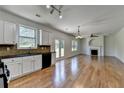 Open-concept kitchen and living room with hardwood floors, white cabinets, fireplace and backyard view at 3168 Sag Harbor Ct, Buford, GA 30519