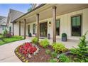 Charming front porch with wood columns, lush landscaping, and elegant lighting, creating a welcoming entrance at 131 Forsyth Park Ln, Woodstock, GA 30188