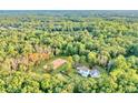 Expansive aerial view of the estate featuring a pristine white house, horse-training paddock, and surrounded by dense forest at 2203 Arbor Hill Rd, Canton, GA 30115