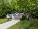Exterior view of home with green landscaping, trees, driveway, and an attached two-car garage at 245 Scotch Pine Ct, Alpharetta, GA 30022