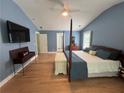 A well-lit bedroom with wooden floors, a ceiling fan, a four-post bed, and tasteful decor at 6725 Grove Meadows Ln, Cumming, GA 30028