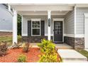 Inviting front porch with stone accents, manicured landscaping, and a stylish front door at 9007 Jim Purcell Dr, Covington, GA 30014